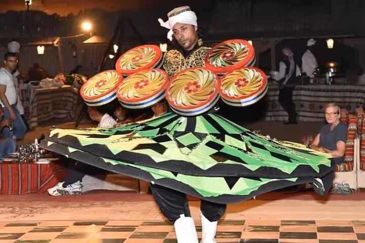 Tanoura dancer spinning in colorful skirt at Dubai desert safari camp, evening BBQ dinner and live show
