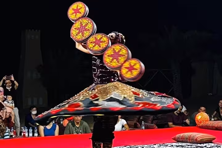A traditional Tanoura whirling dancer balancing colorful spinning discs at Abu Dhabi desert safari live show night entertainment.