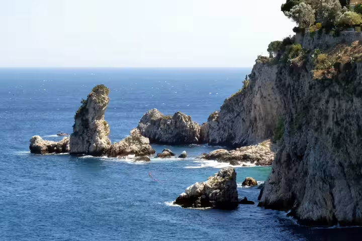 Rocky sea stacks and cliffs on Taormina coast, Sicily, viewed on a private boat tour along the Ionian Sea