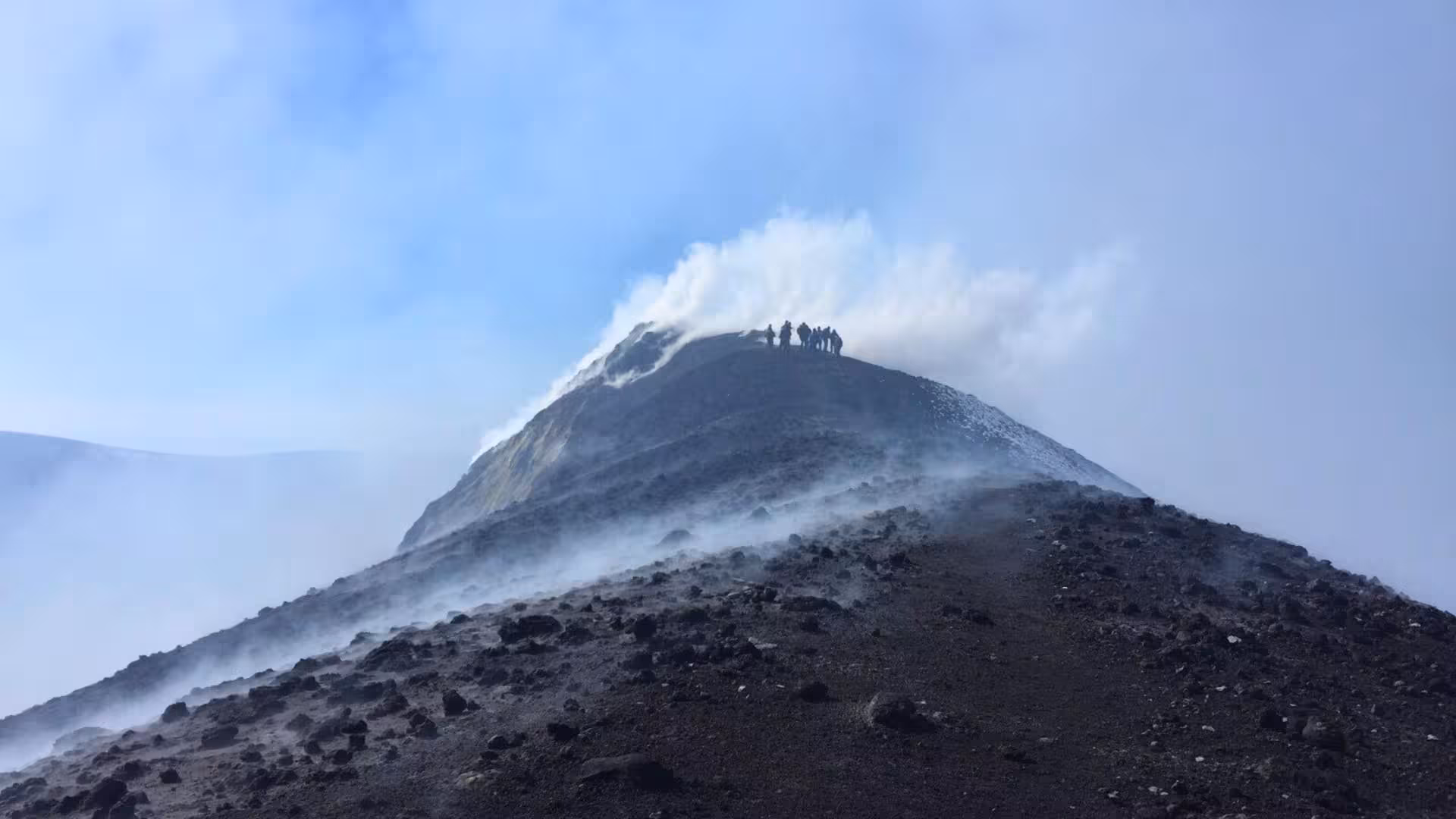 Hikers trekking on the smoky crater of Mount Etna near Taormina, offering a thrilling volcanic adventure experience.