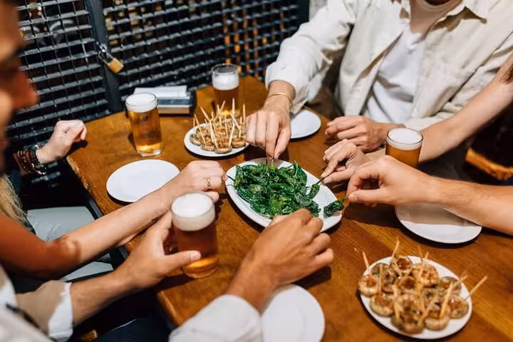 Friends sharing a vibrant tapas spread with drinks, highlighting lively social dining in Santiago Old Town's culinary tours.