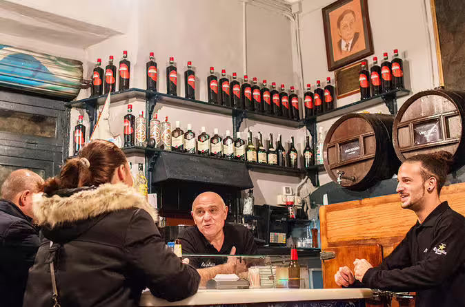 Cozy tapas bar with patrons enjoying wine and conversation, surrounded by shelves of Spanish wine bottles.