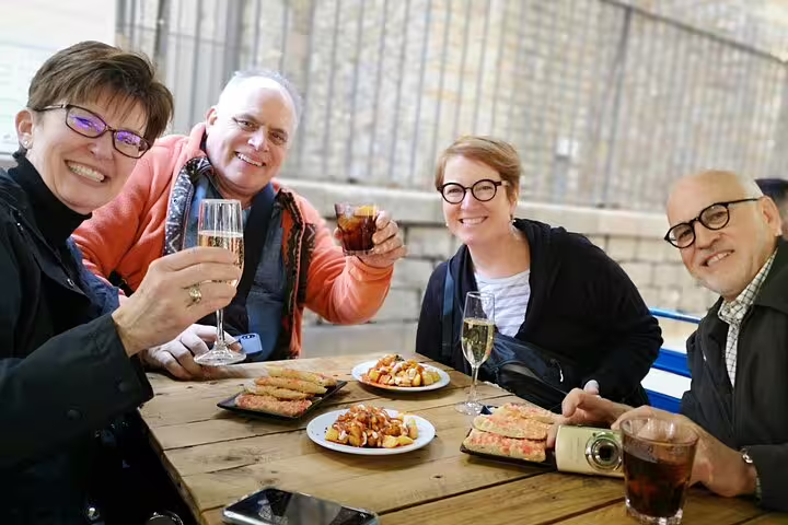 Group enjoying tapas and wine at a rustic table in Barcelona, perfect for a private tour with authentic Spanish cuisine and culture.