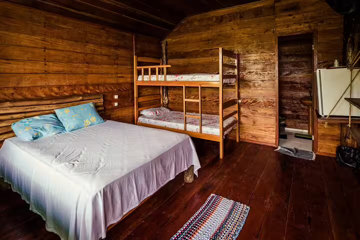 Enjoy cozy accommodations with a double bed and bunk beds in Tapiri Rio Negro Lodge's wooden jungle cabin.