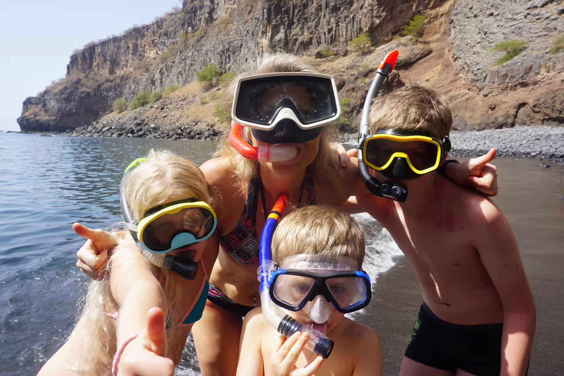 Family with snorkel gear posing happily on Tarrafal Beach during a snorkel adventure.