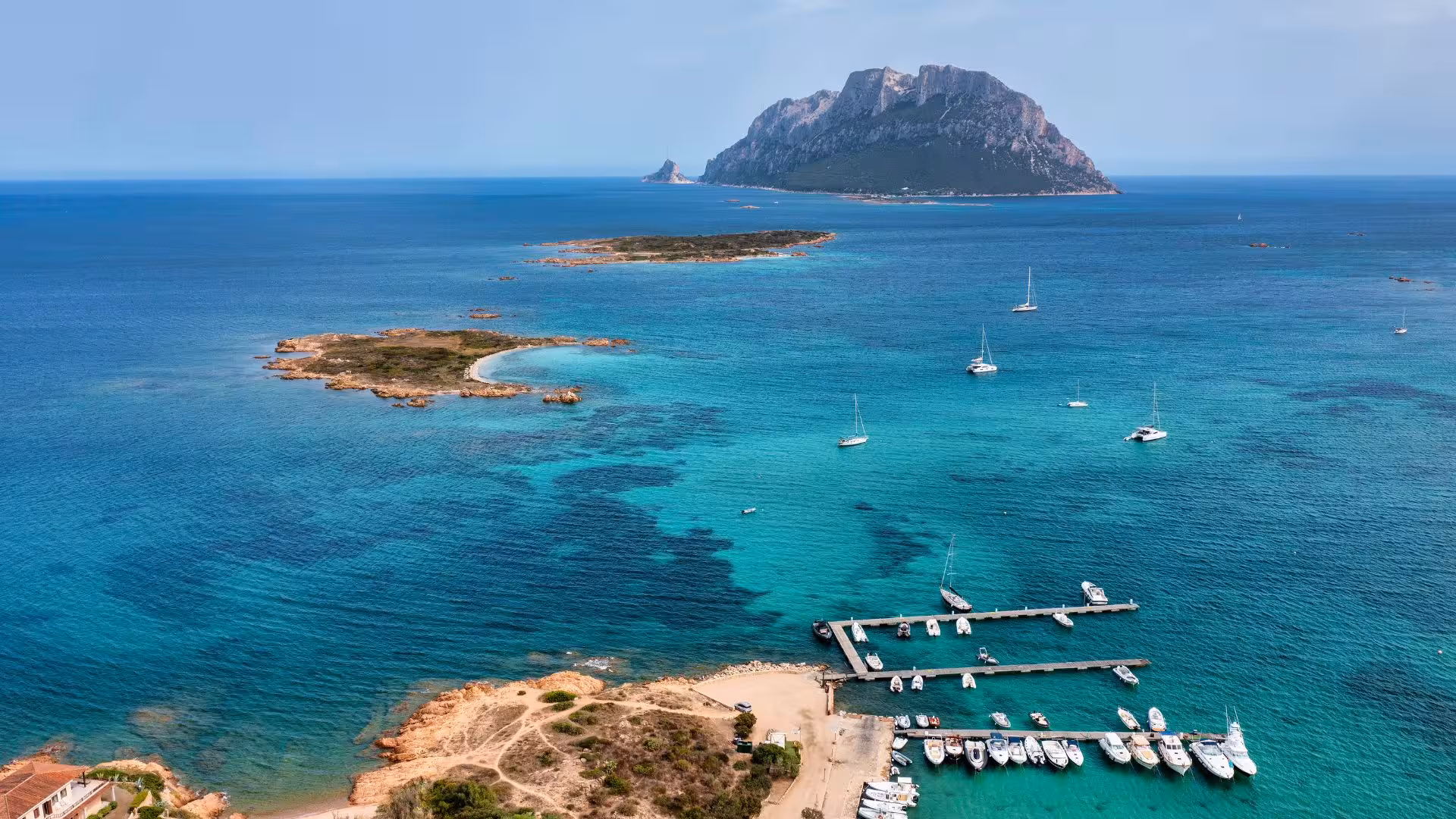 Aerial view of Tavolara Island with yachts in turquoise waters, perfect for a private dinghy tour from Porto Rotondo.