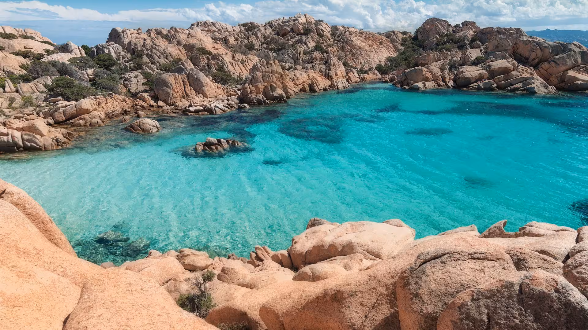 Crystal-clear turquoise waters and rocky landscape at Tavolara, showcasing the beauty of Sardinia's coast.