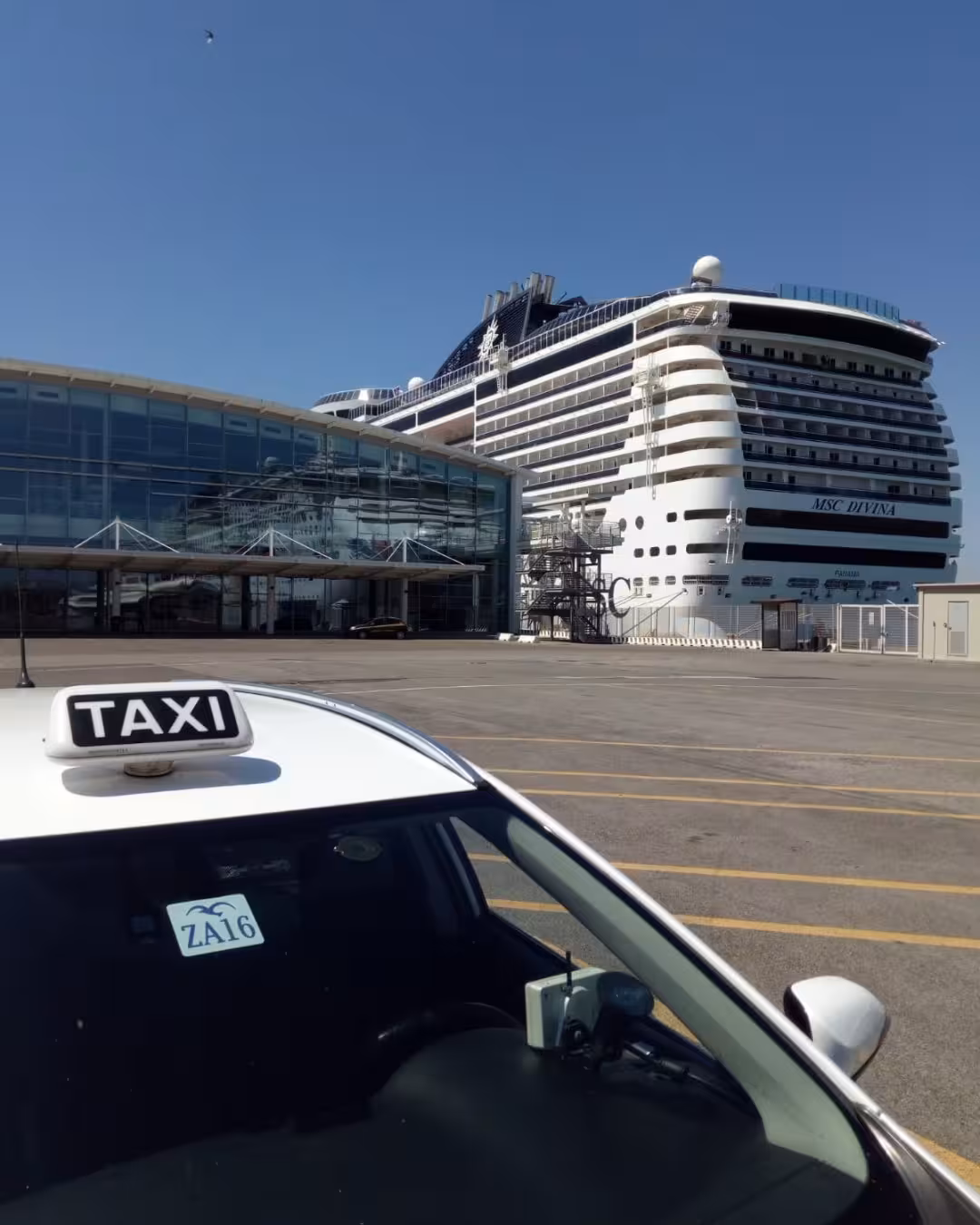 Taxi waiting at Civitavecchia port with a cruise ship in the background for Fiumicino airport transfers.