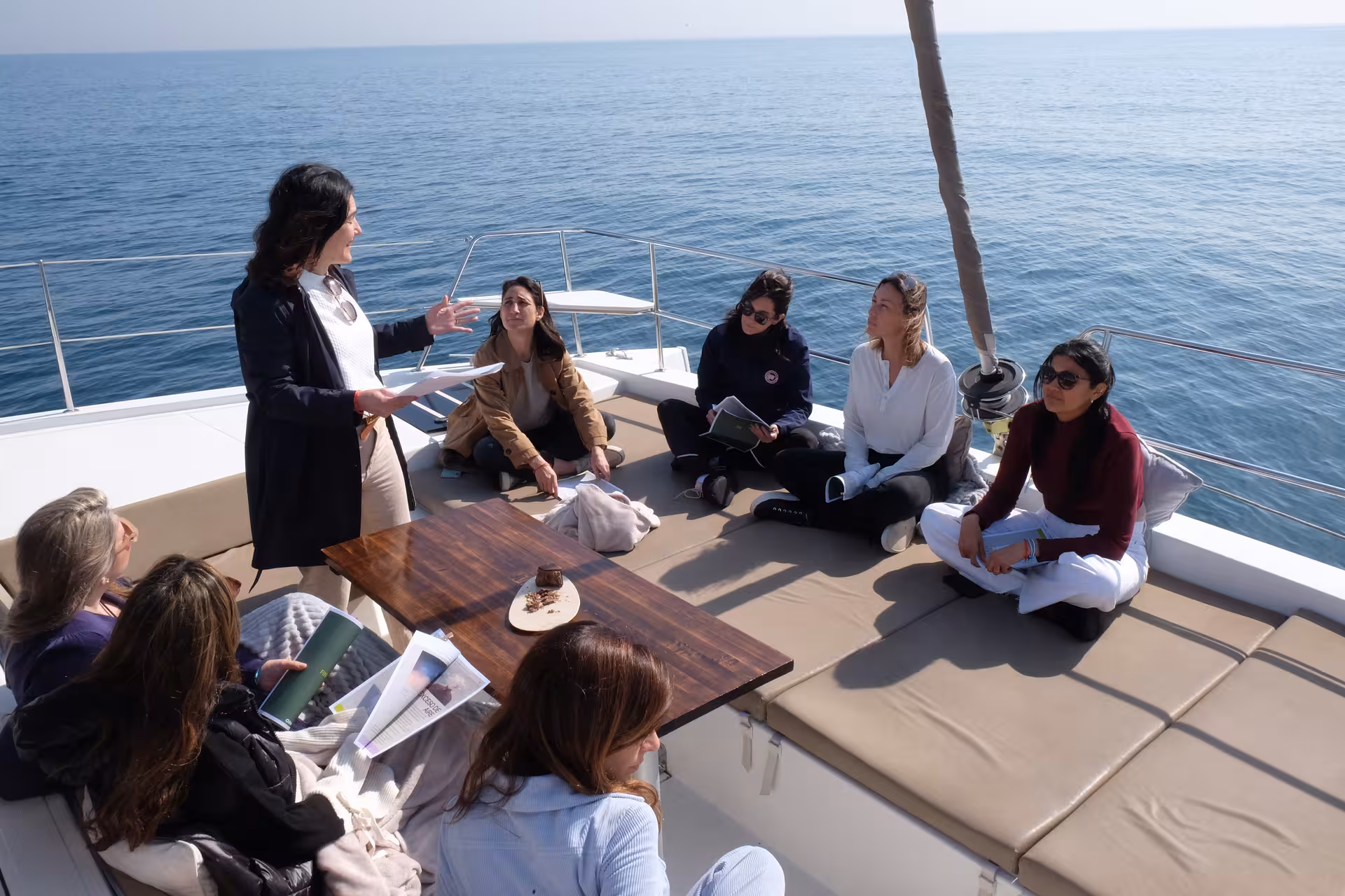 Small group tea ceremony on a boat deck overlooking the sea, guided tasting session with modern mindfulness vibe