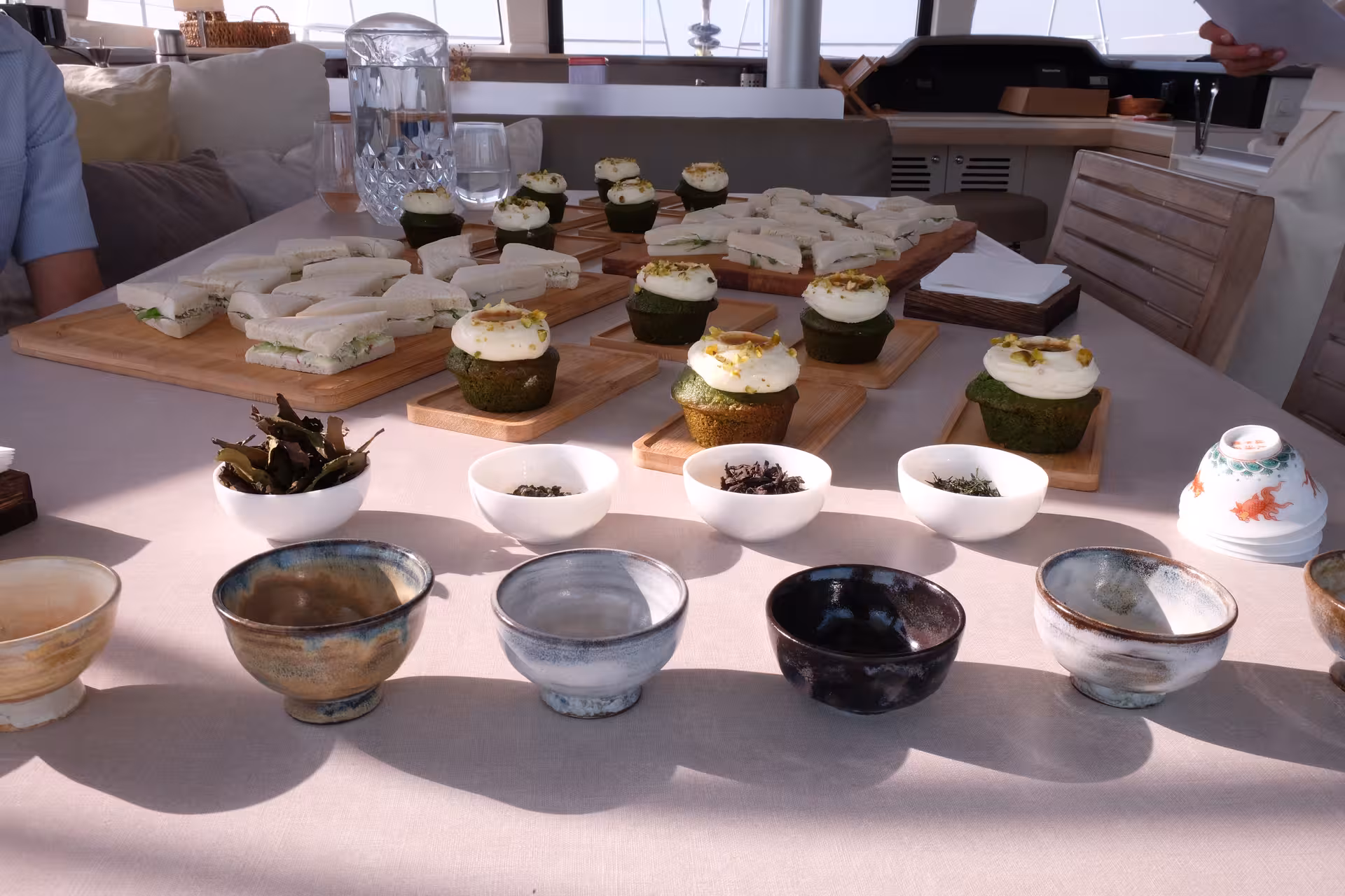 Tea ceremony setup with tasting bowls, loose leaf teas, and matcha cupcakes served with tea on a yacht