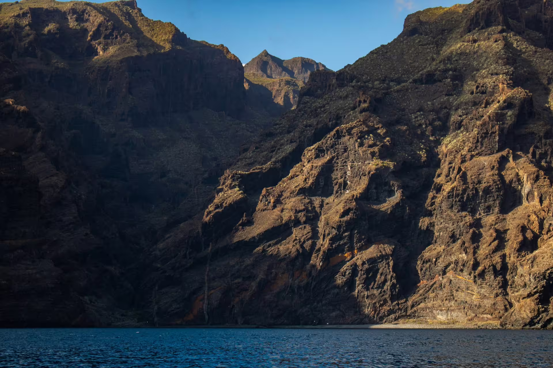 View of Teide's rugged cliffs meeting the ocean under a clear blue sky, perfect for a magical day tour.