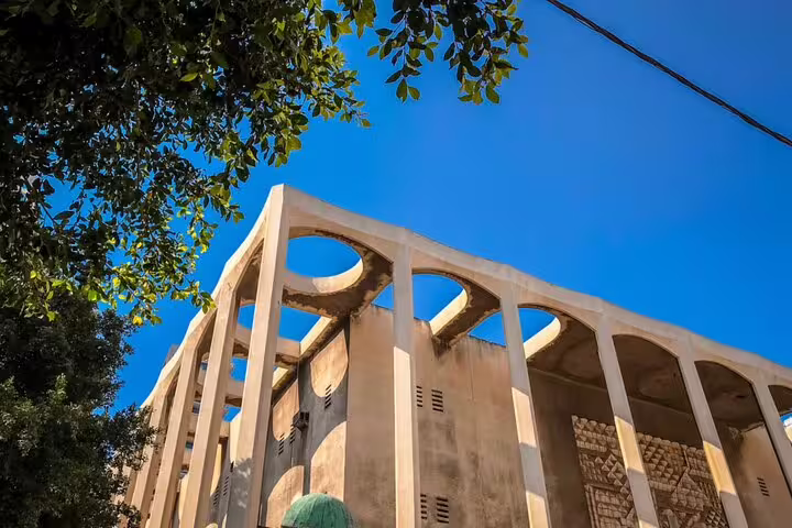 Historic modernist building with arched colonnade facade under blue sky in Tel Aviv