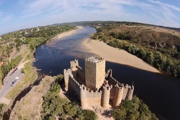 Aerial view of a medieval Templar castle by a winding river, showcasing the landscape on a Private Tour of Templars.