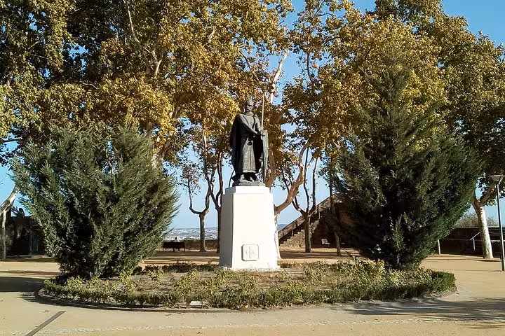 Statue of a Templar knight surrounded by tall trees in a tranquil park setting, ideal for a Private Tour of Templars.