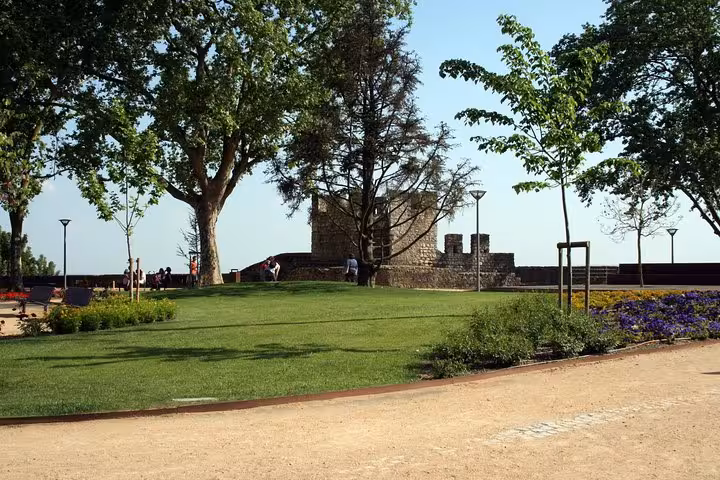Scenic view of a historic stone wall and lush garden on a sunny day during a Private Tour of Templars.