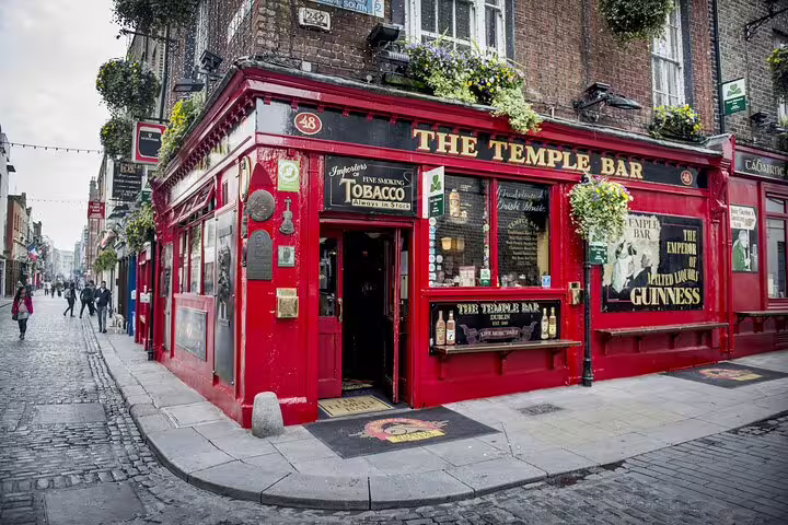 The Temple Bar pub exterior with red facade on cobblestone street corner in Dublin old town