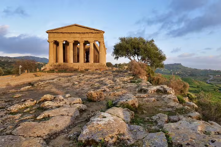 Sunset view of the Temple of Concordia and rocky landscape in Agrigento’s Valley of the Temples on a private Kolymbethra tour