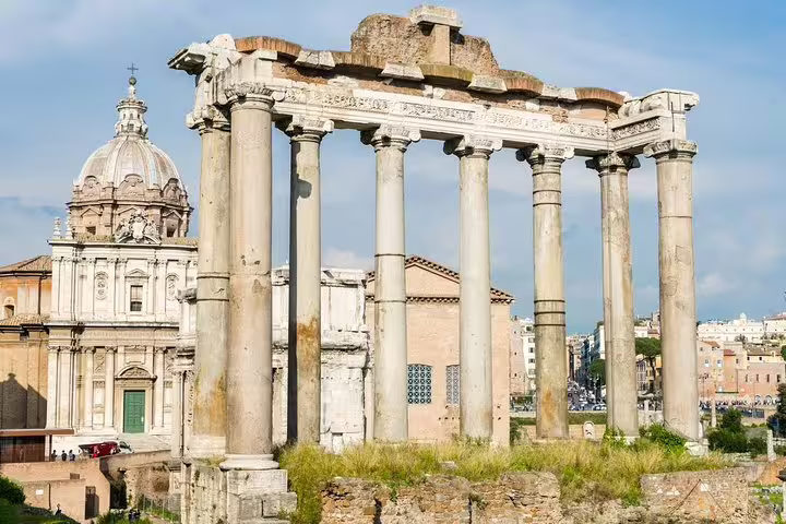 Temple of Saturn columns rising over the Roman Forum with church backdrop on a Colosseum and Palatine Hill guided tour