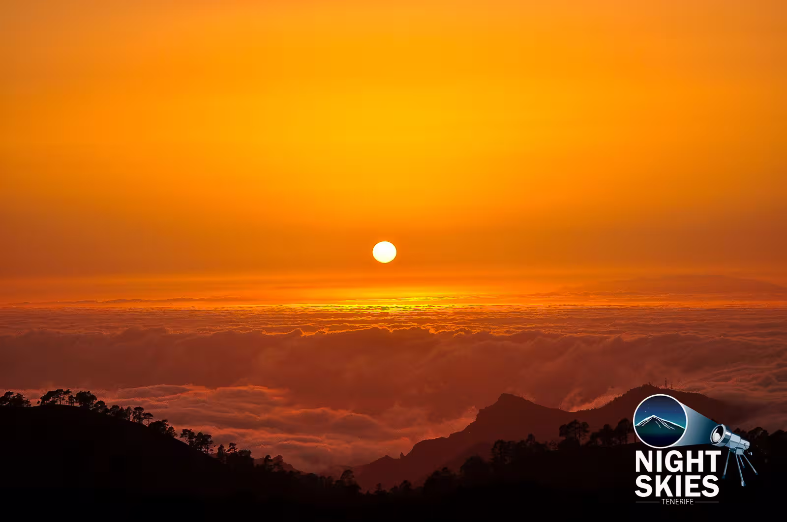 the sun setting in an orange sky above a sea of clouds with mountains and forest below