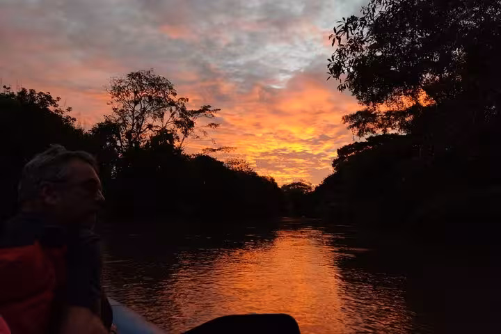 Travelers enjoying a vibrant sunset on the Tenorio River, perfect for wildlife safari and bird watching tours.