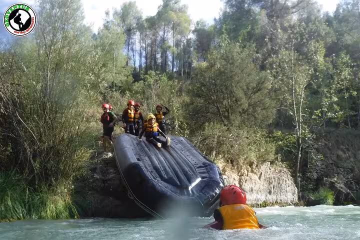 Teruel rafting adventure as guides flip an inflatable raft near the riverbank, team in helmets and life vests