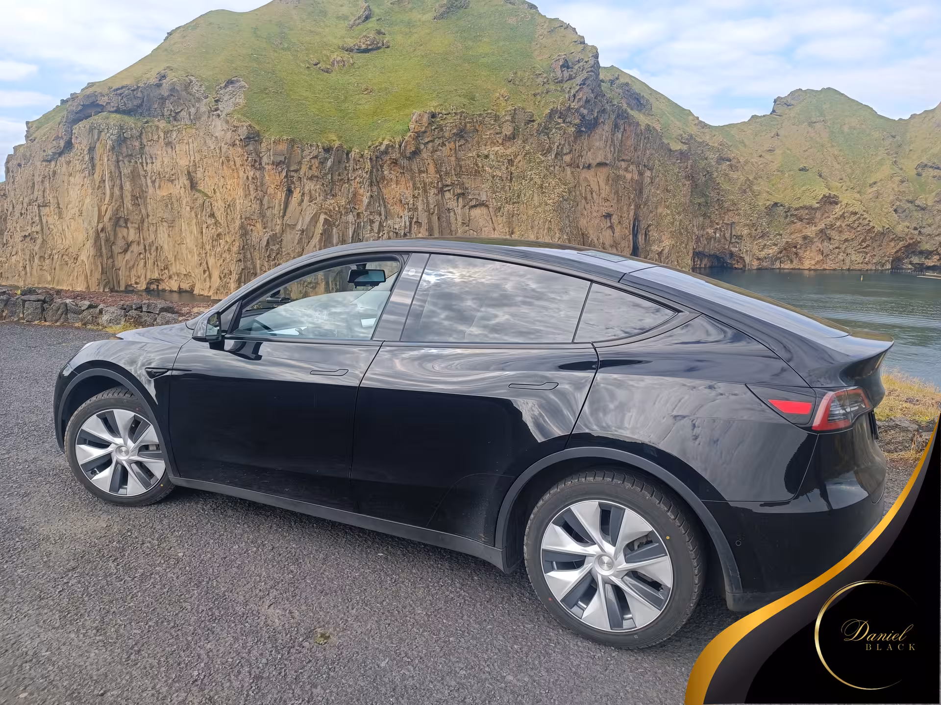 Black Tesla private airport transfer from Reykjavík to KEF, scenic Iceland cliffs and coast in background