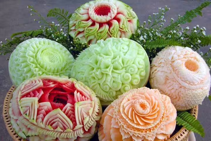 Beautifully hand-carved watermelons and melons showcasing intricate floral patterns in a professional Thai carving class