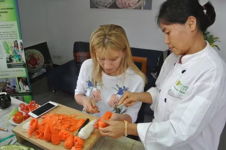 Professional Thai carving instructor teaches a student to sculpt carrots and tomatoes in a half-day carving class