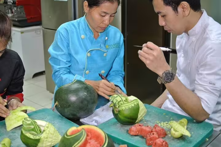 Expert Thai chef demonstrates detailed watermelon carving techniques during a hands-on professional carving class