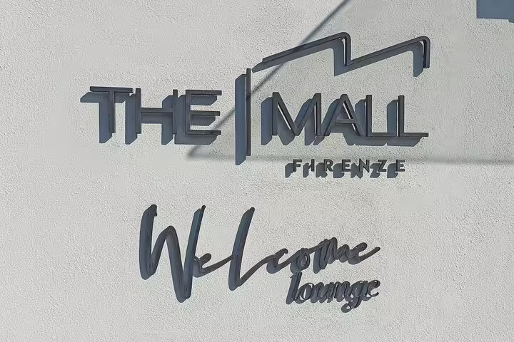 Entrance sign for The Mall Firenze Welcome Lounge, starting point for private chauffeur outlet shopping near Florence