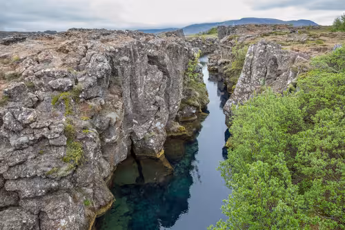 Crystal clear water flowing through rocky lava canyon fissure at Thingvellir National Park, Iceland