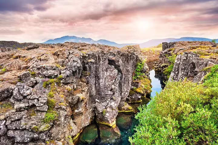 Rocky canyon with turquoise water at Þingvellir National Park, Golden Circle Iceland, mountains in background