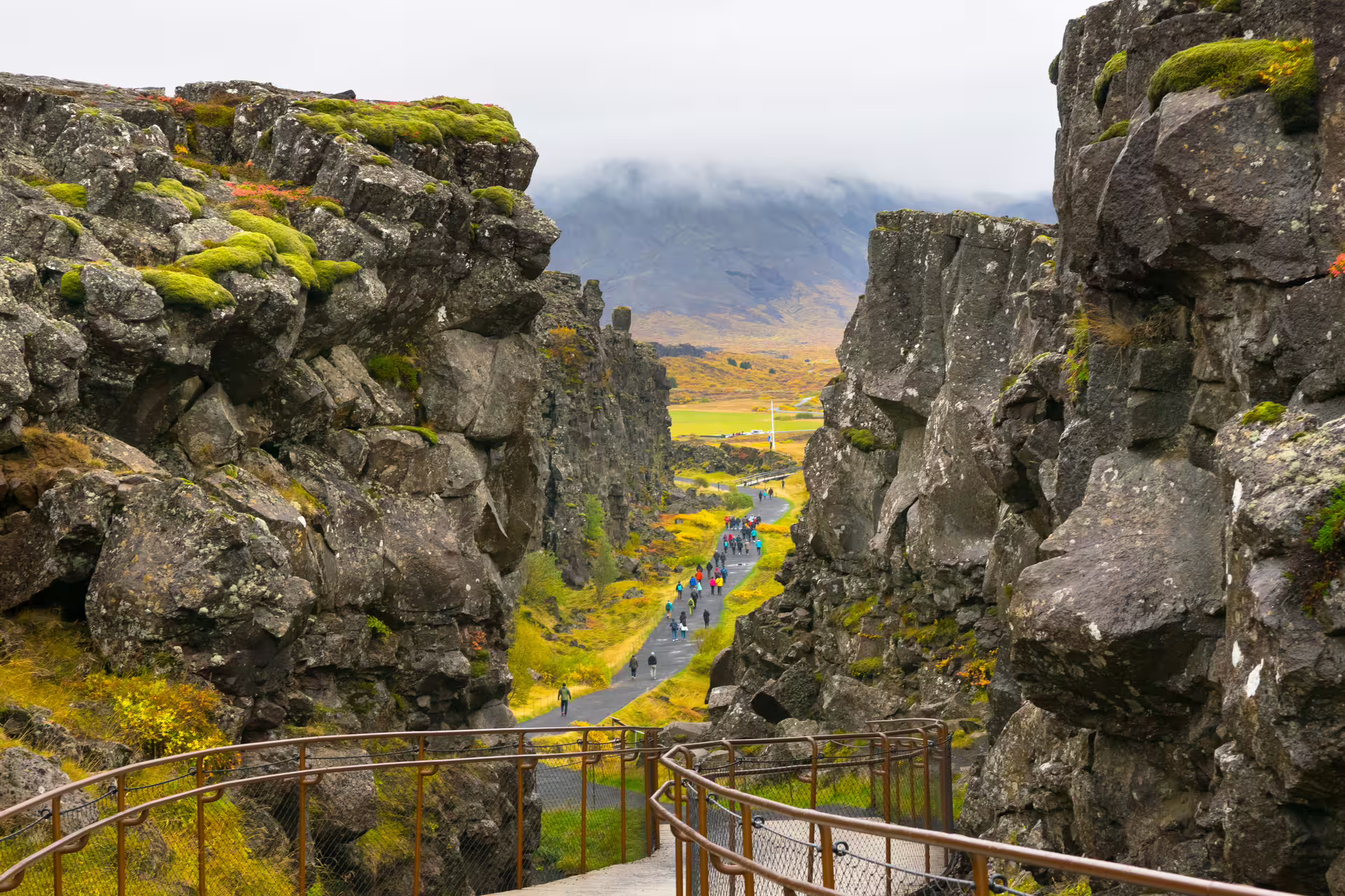 Tourists walking through Þingvellir canyon rift valley on Iceland's Golden Circle route