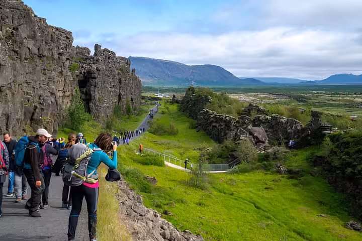 Tourists hiking along rocky canyon path at Þingvellir National Park on Iceland's Golden Circle route