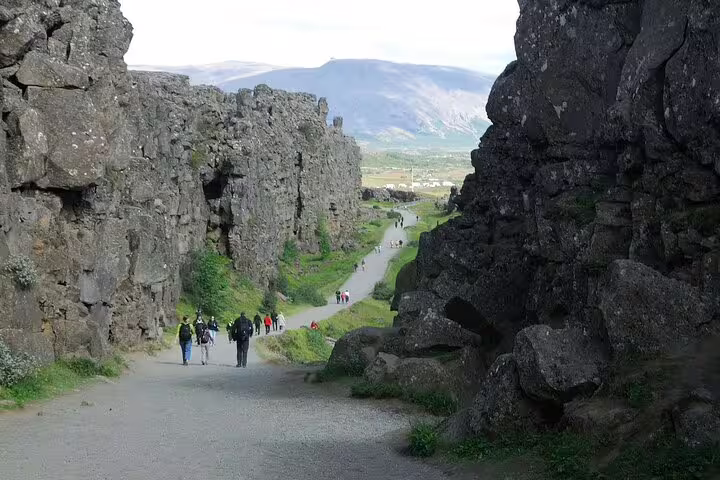 Tourists walking through Almannagjá canyon rift valley at Þingvellir National Park on Golden Circle tour