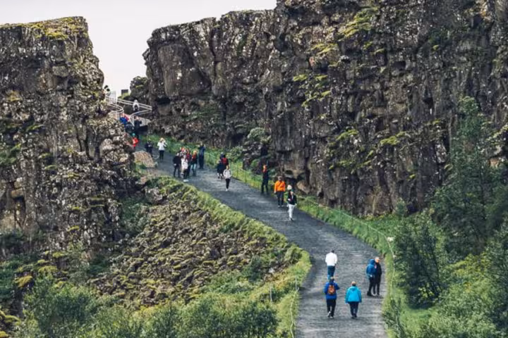 Tourists walking through Almannagjá canyon rift valley at Þingvellir National Park on Golden Circle tour