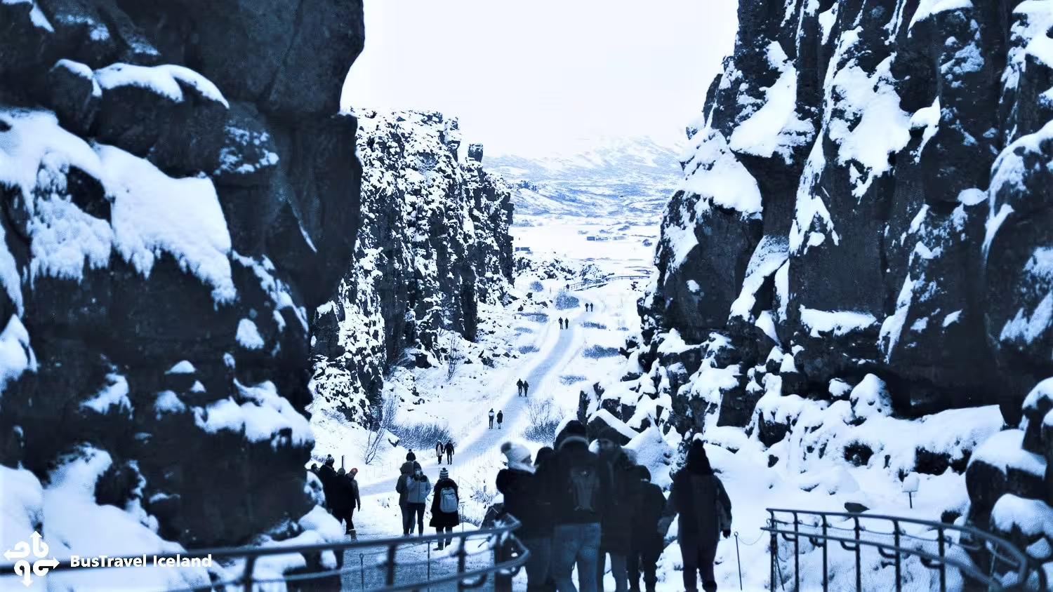 Tourists walking through snow-covered Almannagjá canyon at Thingvellir National Park in winter, Iceland
