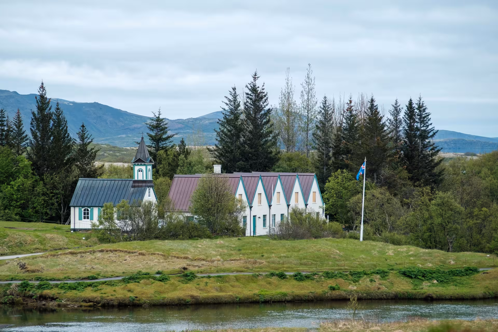 Þingvellir church and historic buildings beside a river with mountains in Iceland's Golden Circle