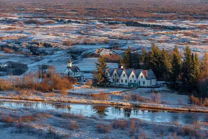 Þingvellir church and farmhouses beside a reflective river in a frost-covered Icelandic landscape