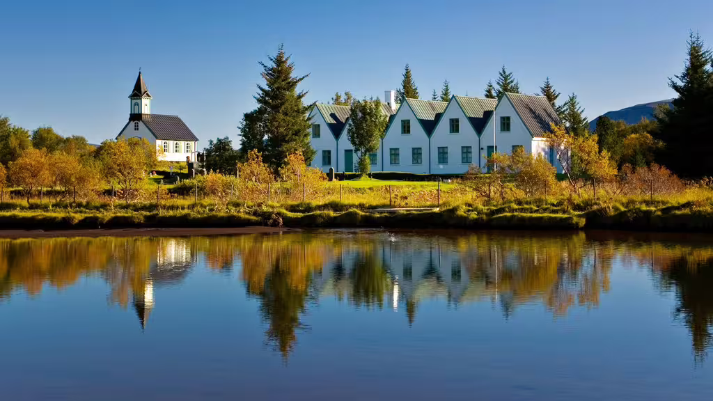 Þingvellir church and white farmhouse reflected in calm lake waters on Iceland's Golden Circle route