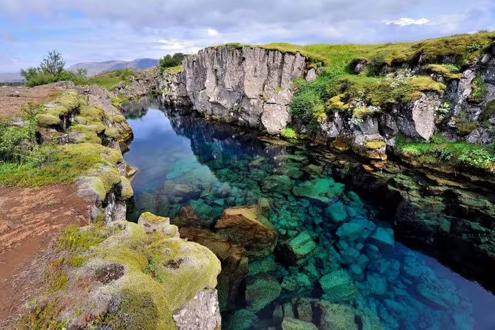 Crystal clear turquoise water filling a rocky lava fissure at Þingvellir National Park, Iceland