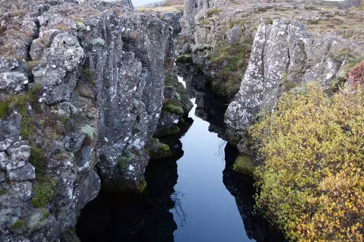 Narrow rocky fissure filled with dark water at Þingvellir National Park, Iceland