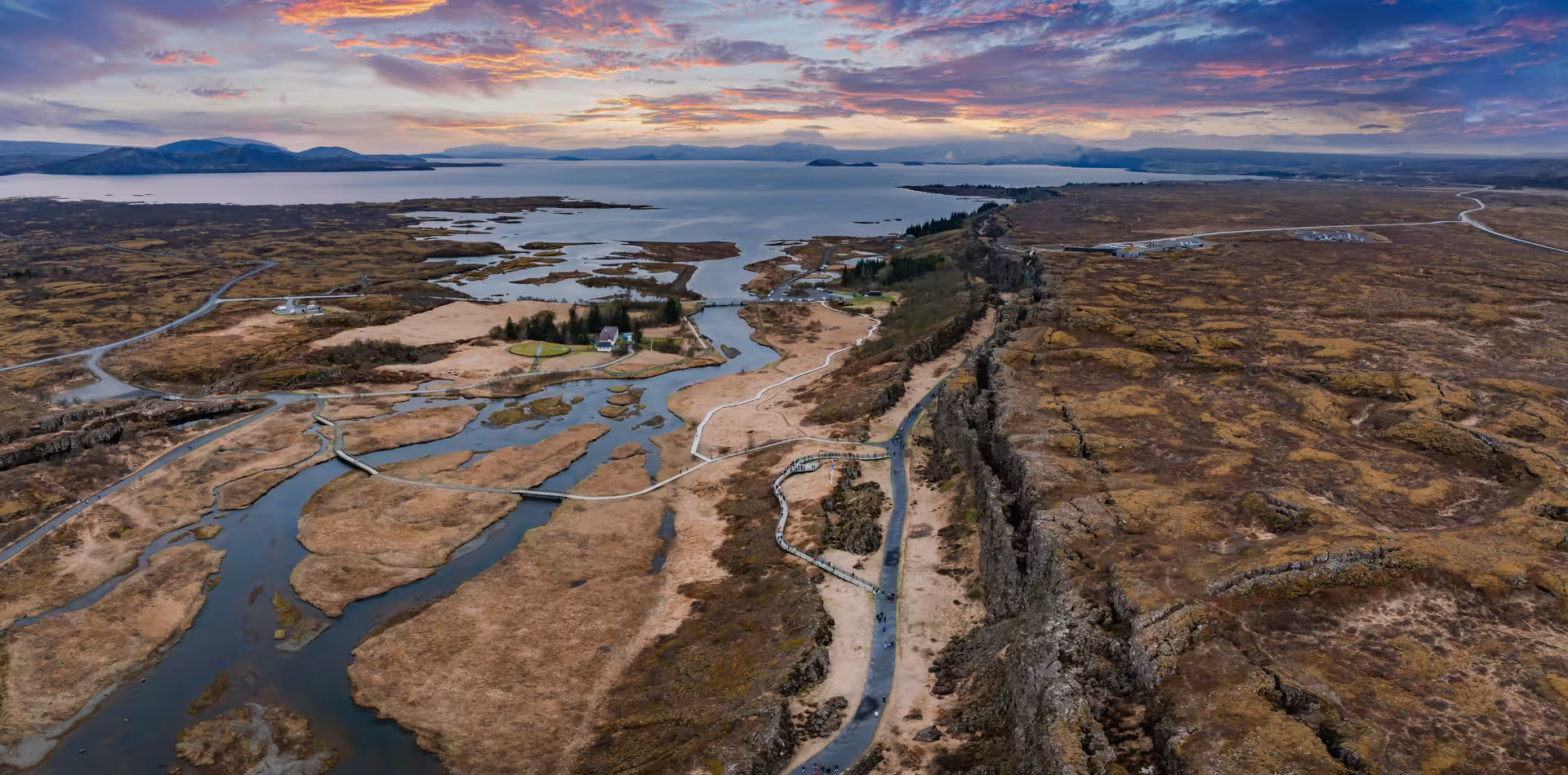 Aerial view of Þingvellir National Park tectonic rift with river channels and Lake Þingvallavatn at sunset, Iceland