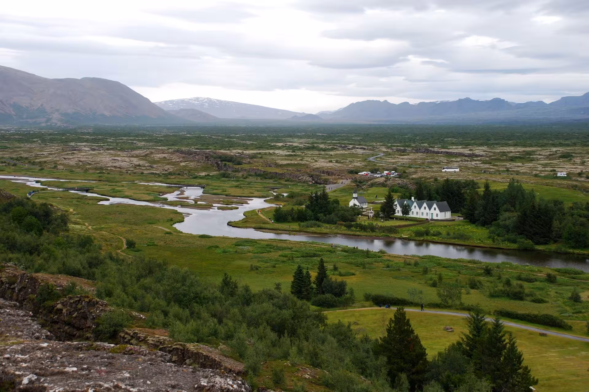 Aerial view of Þingvellir National Park with winding river, white church, and mountains in Iceland