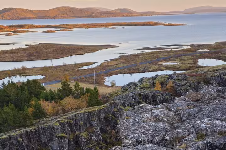Aerial view of Þingvellir National Park with rocky cliffs, lush trees, and lake in Iceland's Golden Circle
