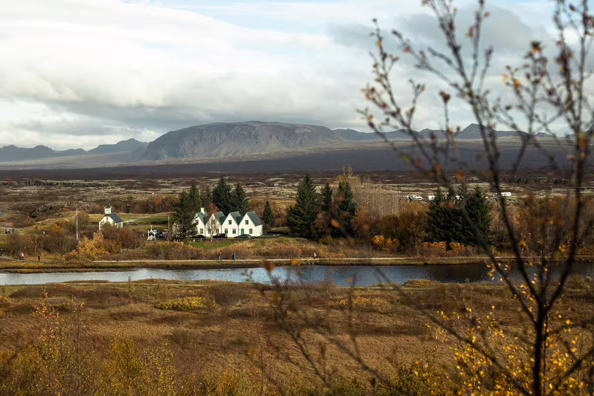 Þingvellir National Park with white farmhouse, river, autumn foliage and volcanic mountains, Iceland Golden Circle