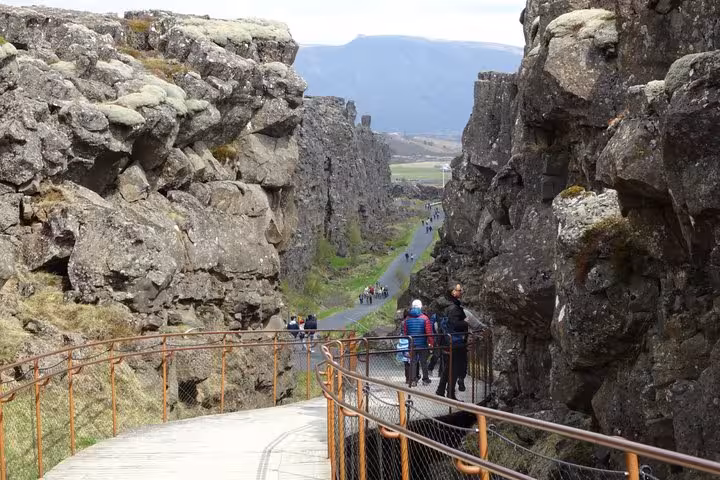 Tourists walking through Þingvellir tectonic rift canyon on Iceland's Golden Circle tour