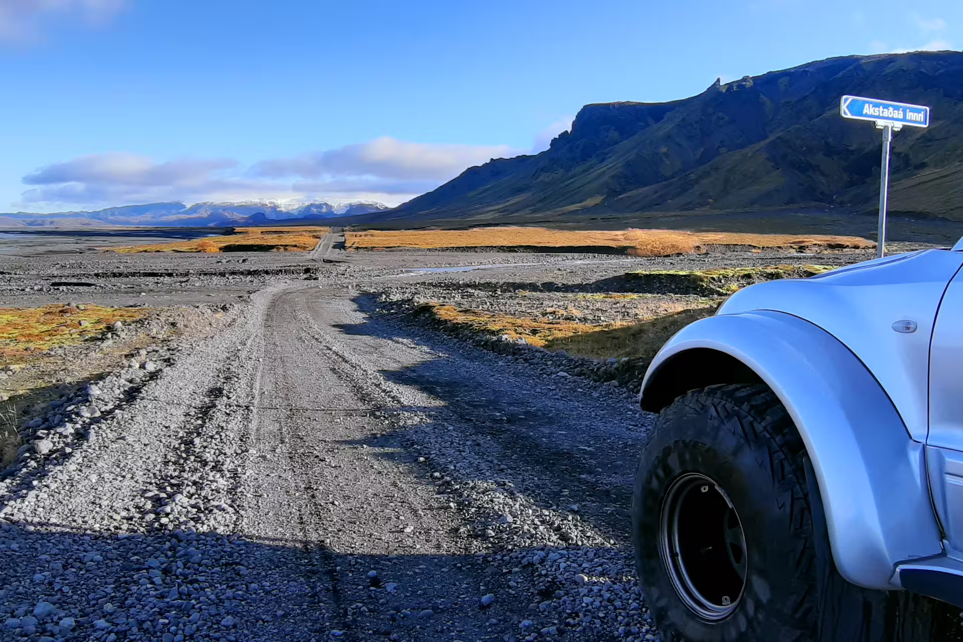 4x4 vehicle on gravel road toward Thorsmork valley with volcanic mountains and glacier backdrop in Iceland