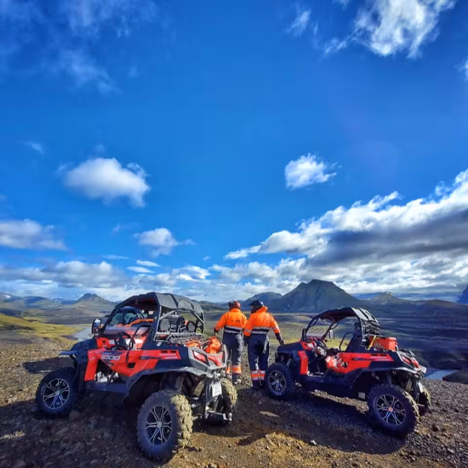 Two red buggy UTVs with guides in orange gear overlooking Thorsmork highland valley, Iceland