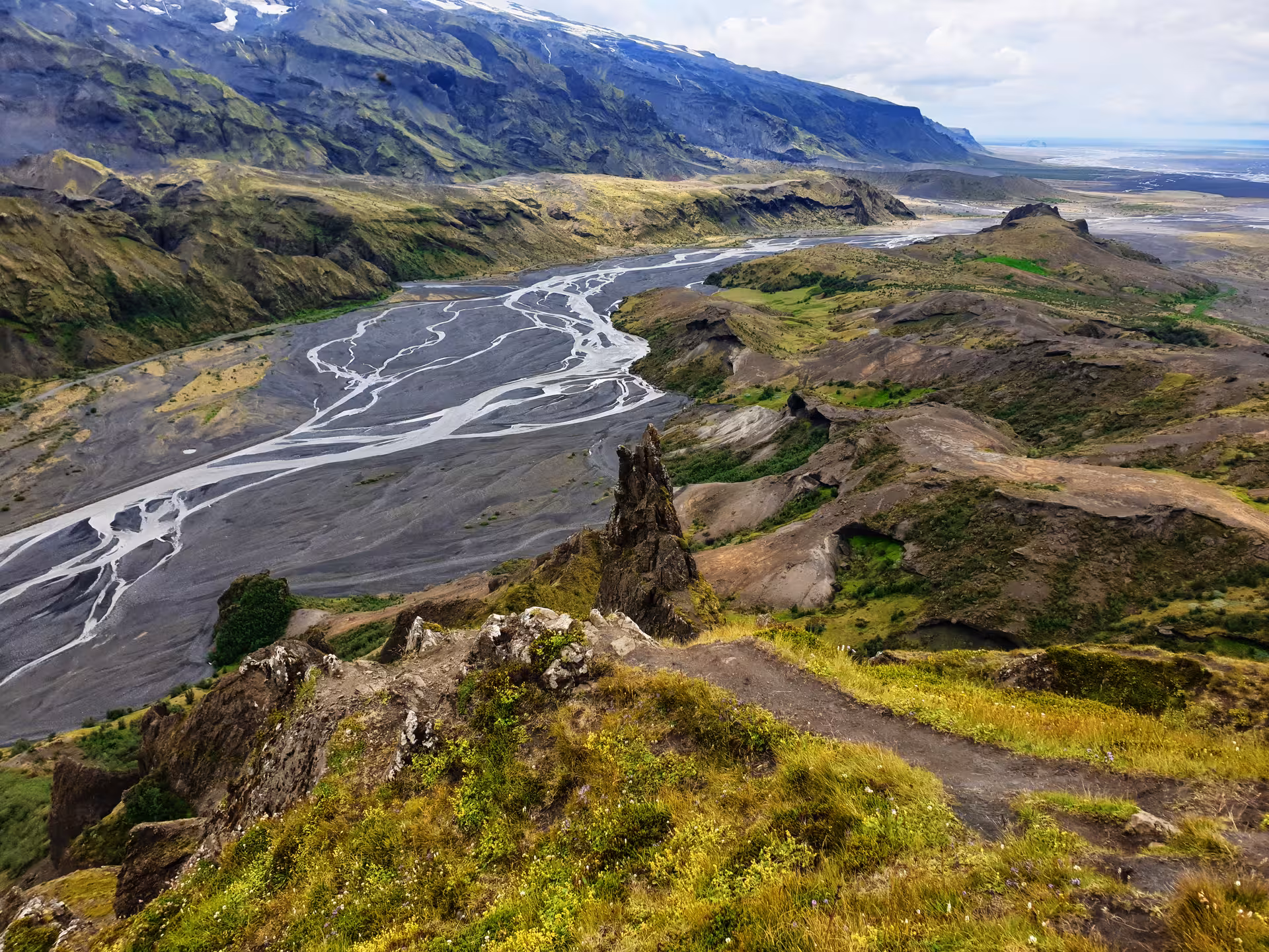 Aerial view of Thorsmork valley with braided glacial river, rocky ridges, and green moss-covered hills in Iceland
